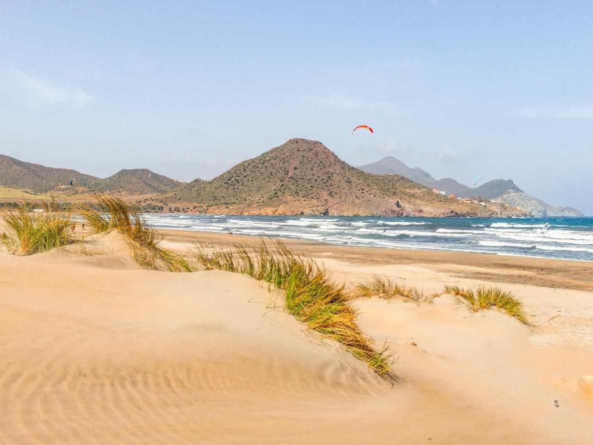 This curved sandy beach is surrounded by dunes and volcanic hills