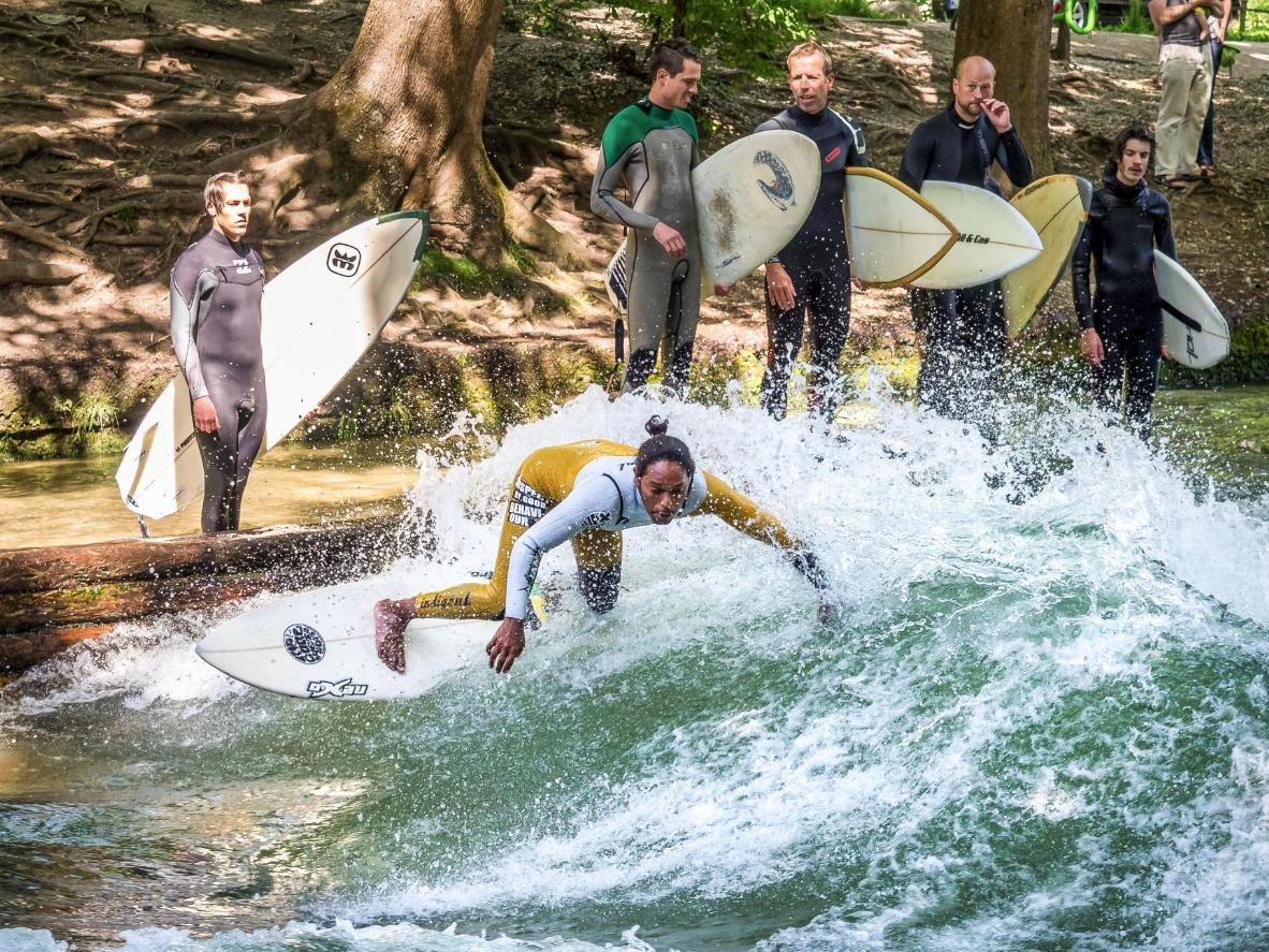 Surfers try their luck on the standing wave of the Eisbach